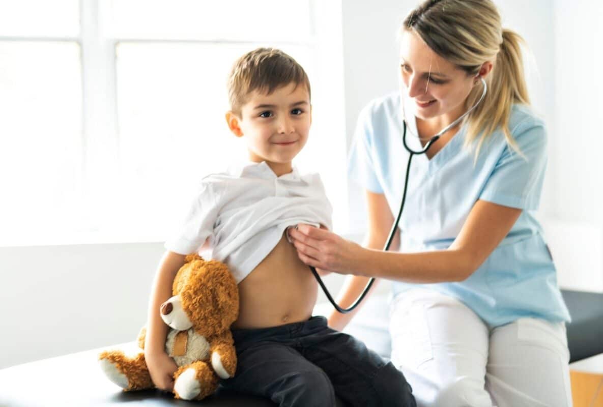 ילד מחייך רגוע בבדיקה אצל רופאה לאחר ניתוח סטומה