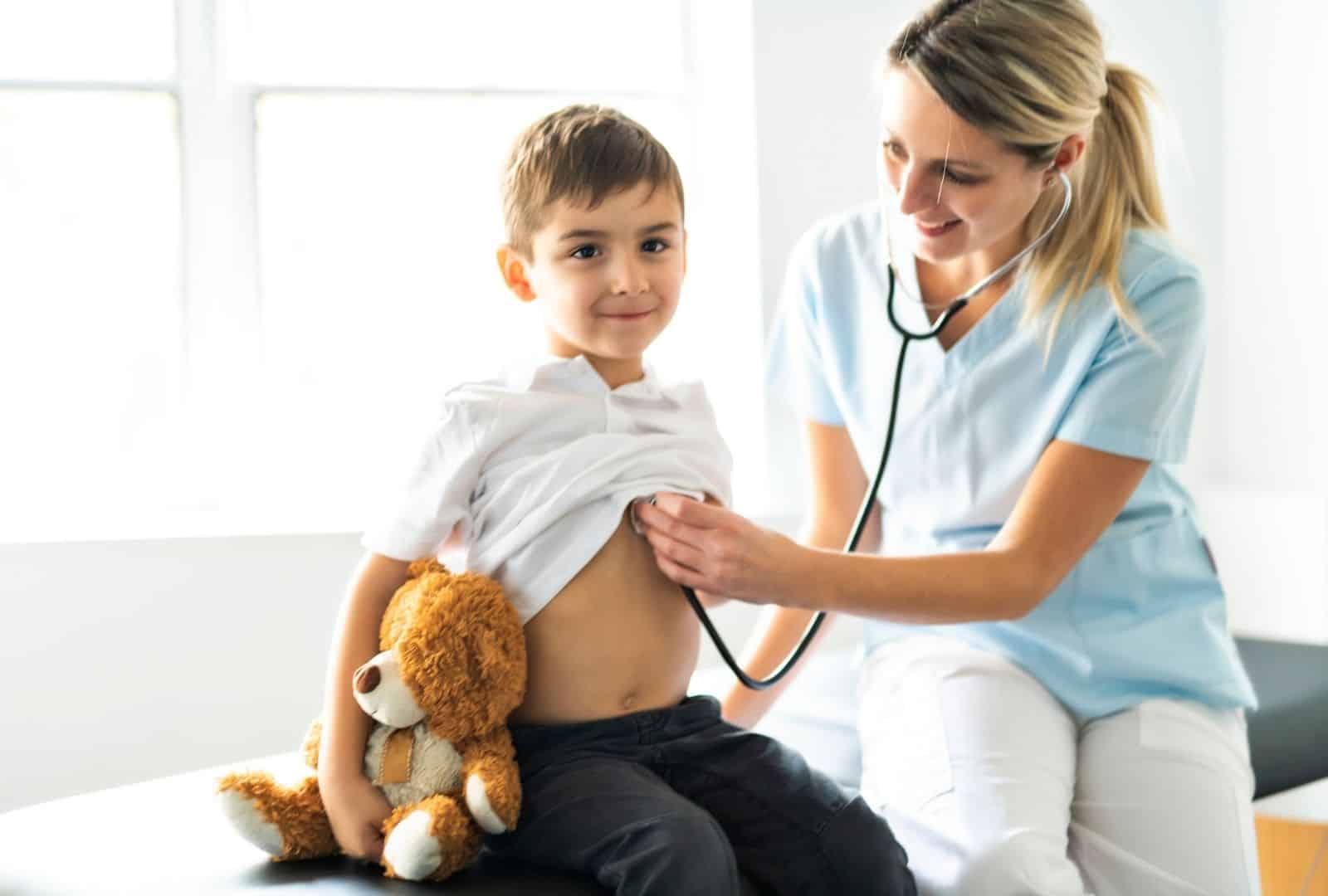 ילד מחייך רגוע בבדיקה אצל רופאה לאחר ניתוח סטומה