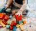 תינוק משחק בקוביות צבעוניות על שטיח – מסמל התפתחות מוטורית וחקר אצל ילדים עם עיכוב התפתחותי